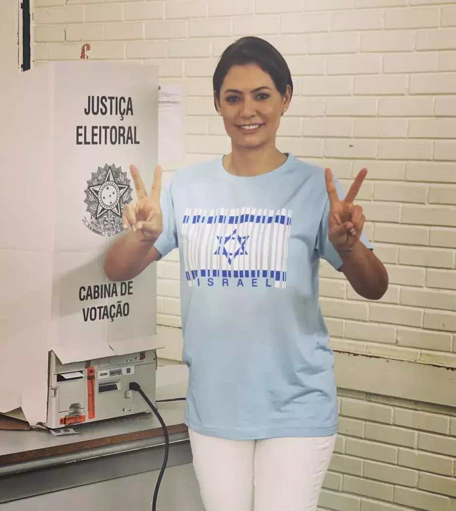 Мишел Болсонаро, евангелска християнка и съпруга на бившия бразилски президент Жаир Болсонаро, гласува през 2022 г., докато носи тениска с израелското знаме